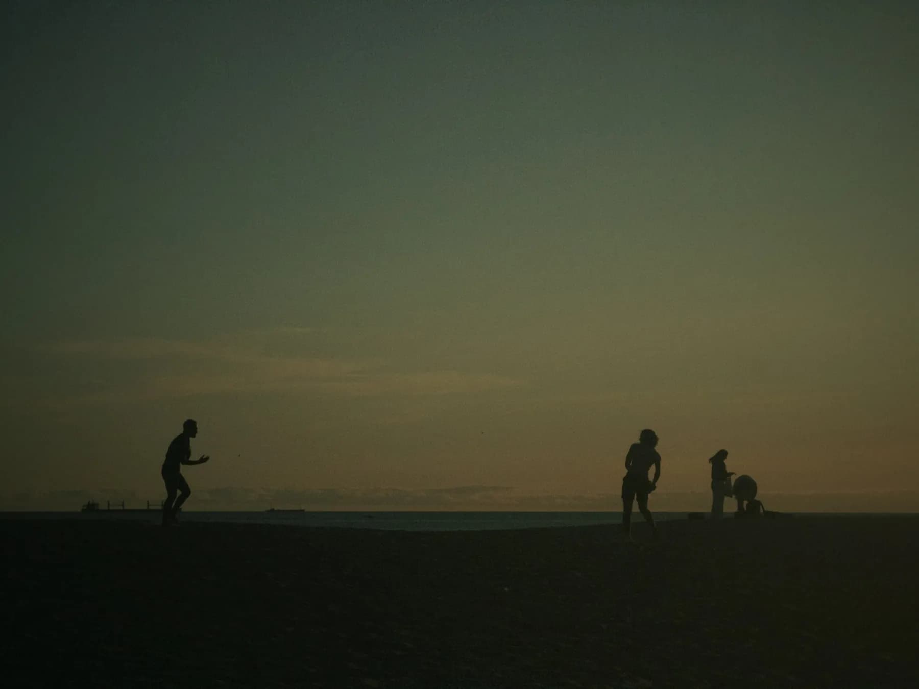 Siluetas de personas jugando en la playa al atardecer