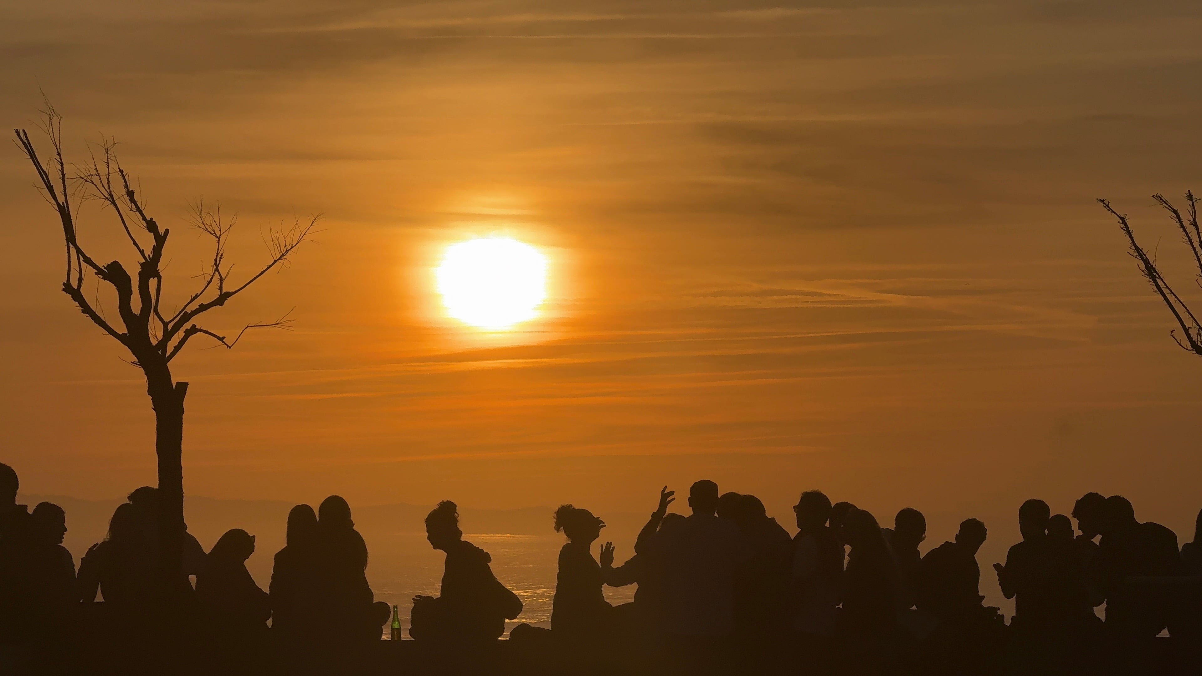 Personas en silueta reunidas frente al sol del atardecer